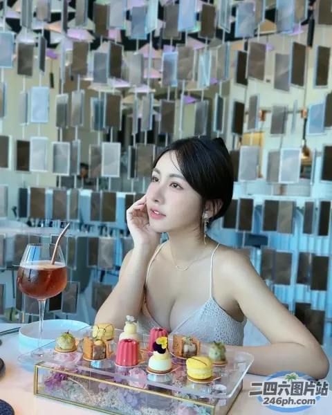 女人坐在一张桌子旁，手里拿着一盘食物和一杯酒