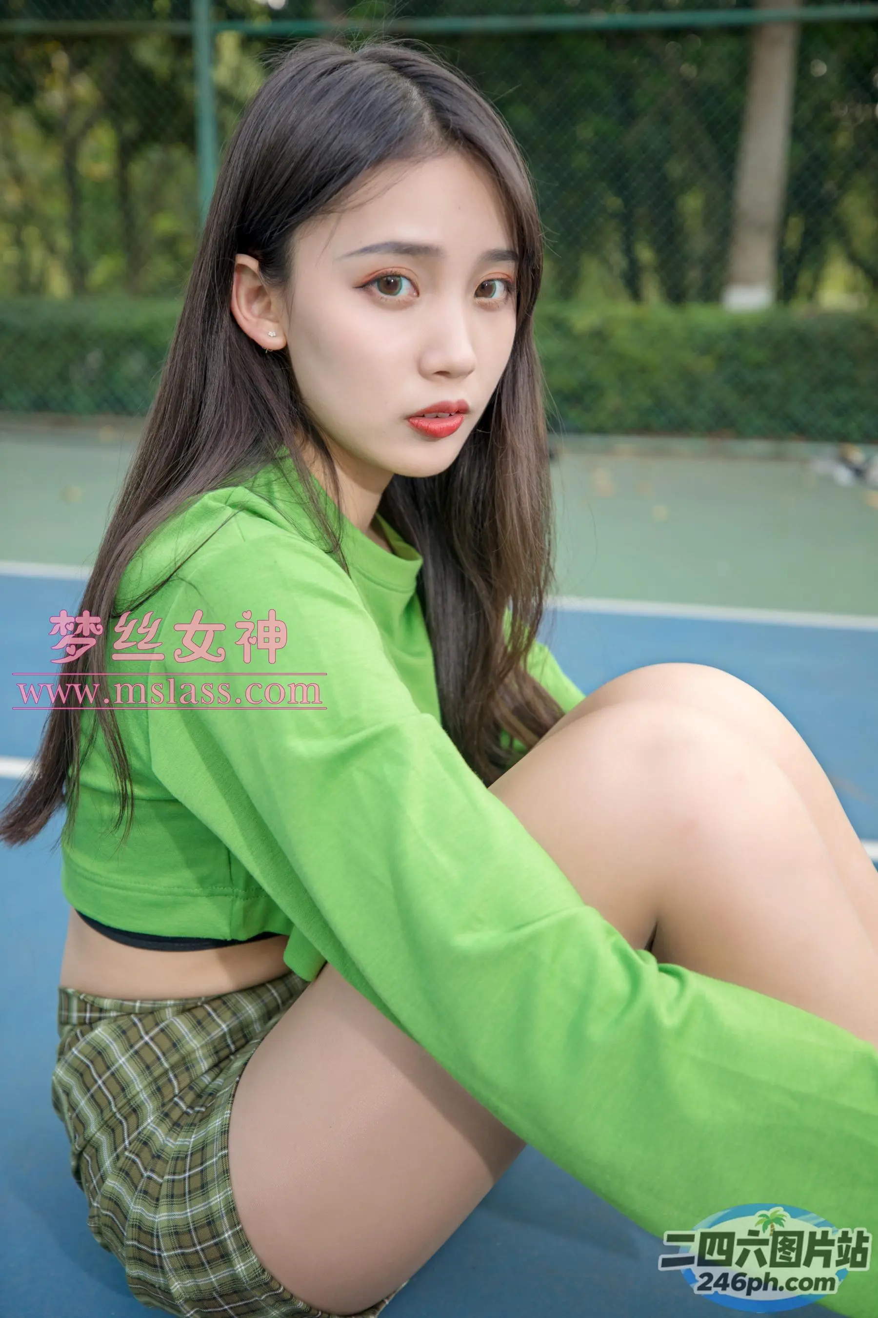 一个女人拿着球拍坐在网球场上的特写