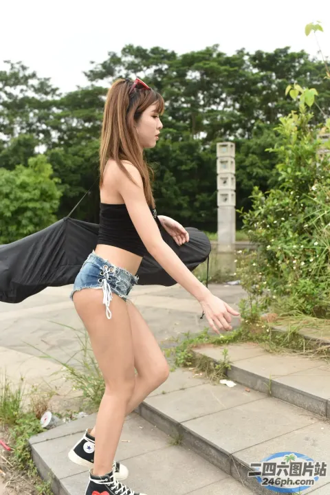 身穿黑色上衣和牛仔短裤的 Araffed 亚洲女性正在走上楼梯
