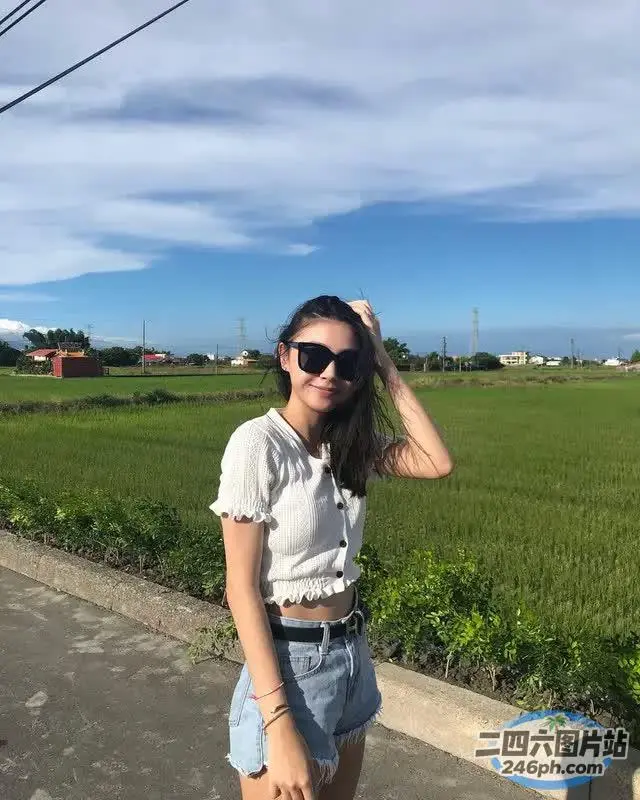 身穿白衬衫和牛仔短裤的 arafed 女子站在田野前