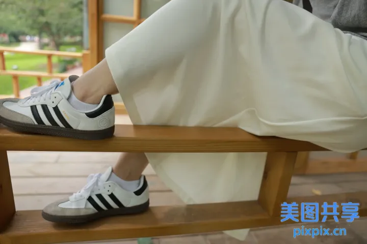 有个女人坐在长凳上，脚踩在长凳上