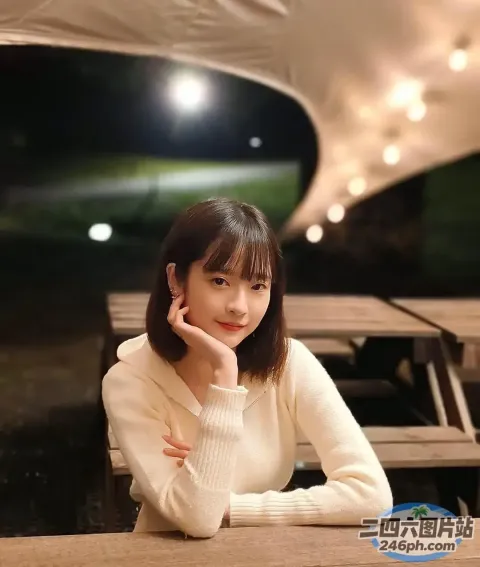 有个女人坐在桌子旁，手里拿着手机