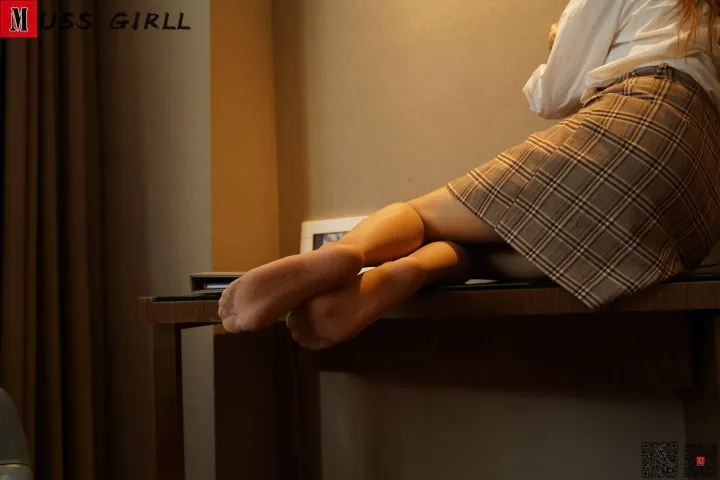 有一个女人坐在桌子上，双腿交叉