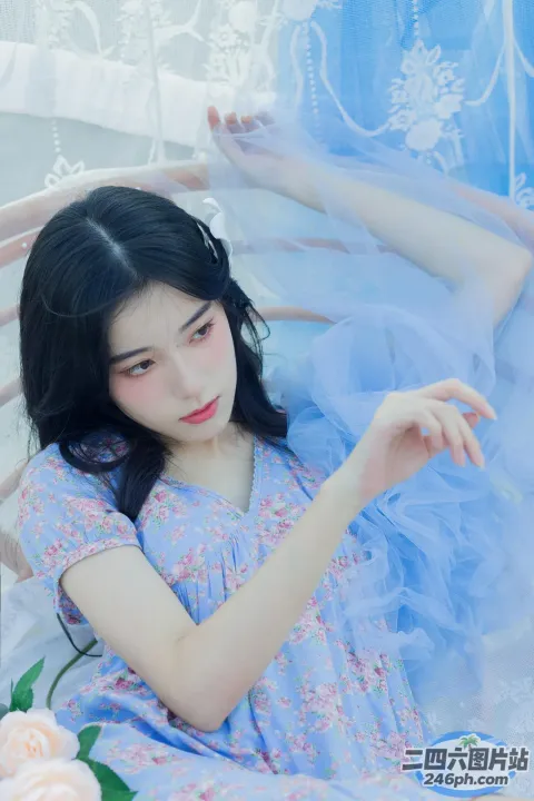 床上坐着一个穿着蓝色连衣裙的年轻女子