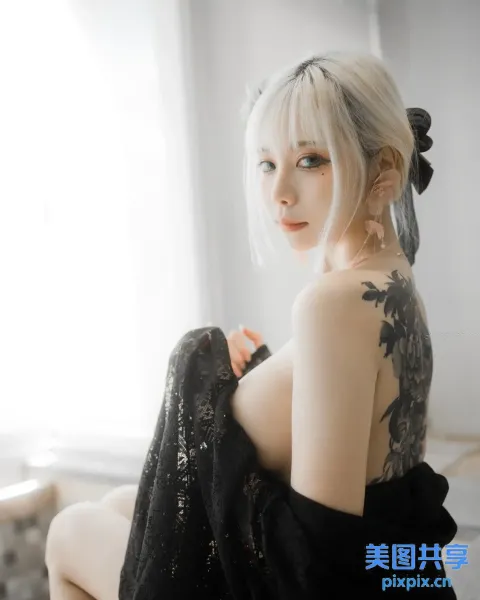 床上坐着一个背上有纹身的女人