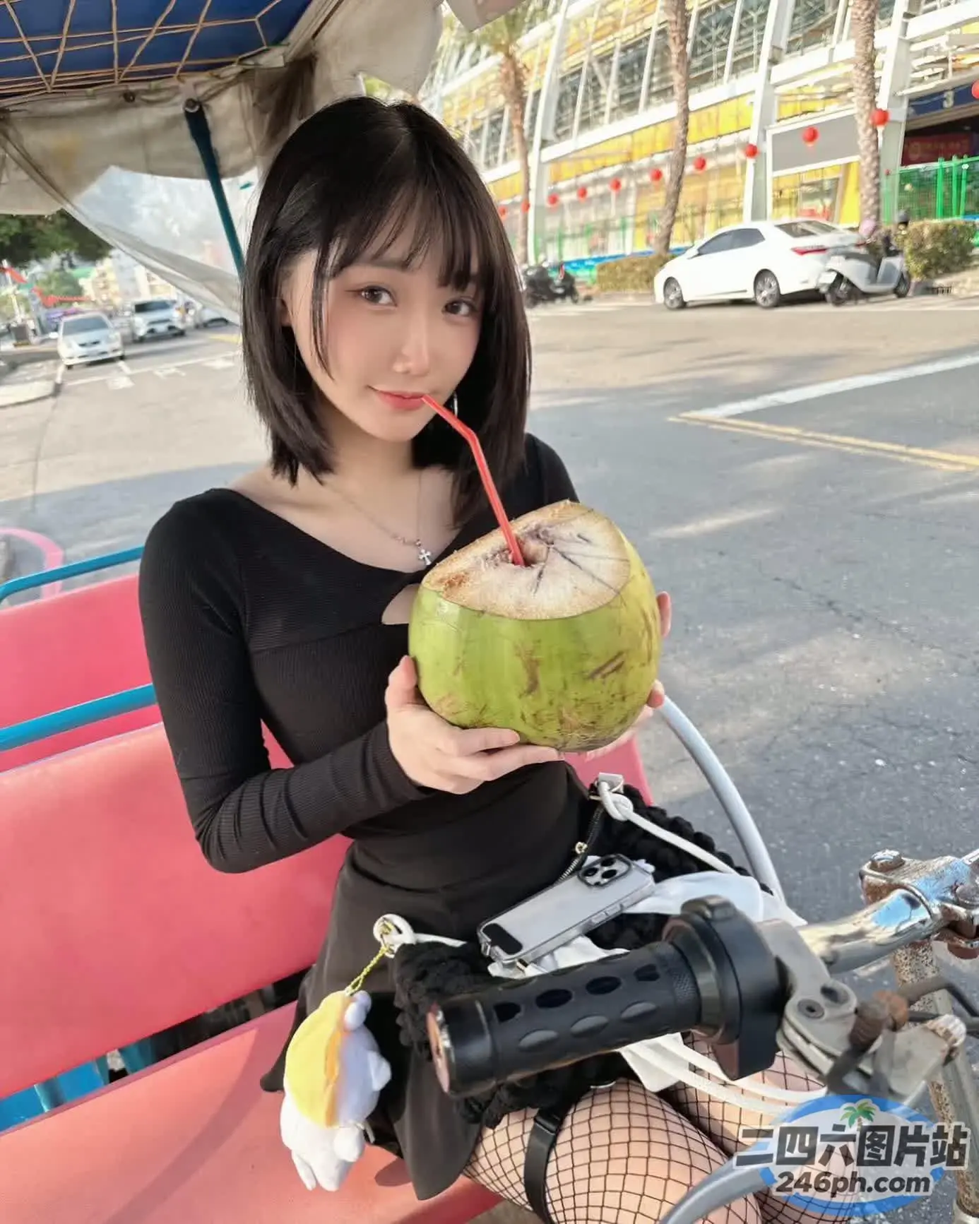 阿拉菲女人坐在长凳上，手里拿着椰子饮料