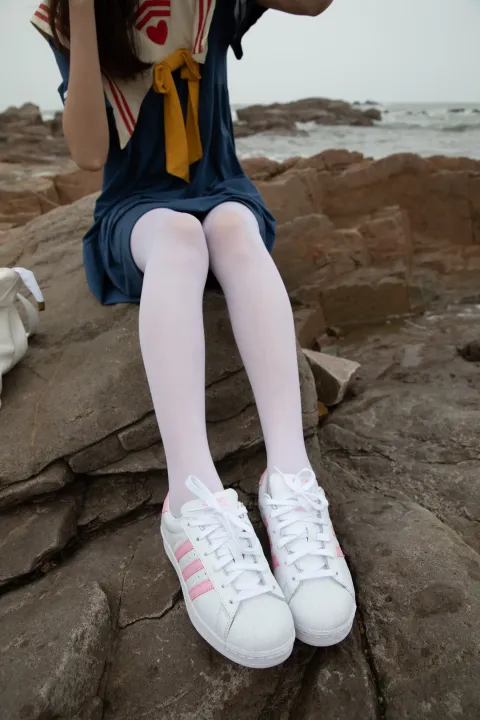 有一个女人坐在岩石上，戴着帽子和袋子