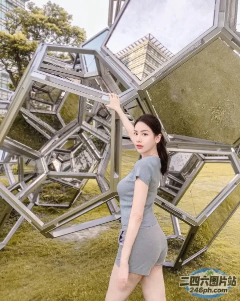 身穿灰色连衣裙的 Arafed 女子站在雕塑前