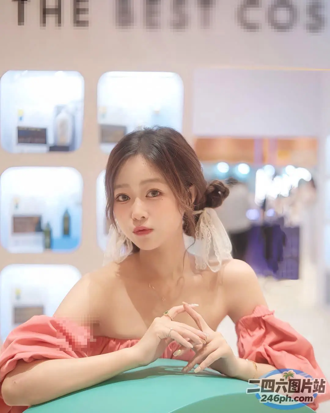 身穿粉红色连衣裙的 Araffe 女子坐在一张放着绿色盒子的桌子旁