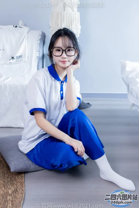 阿拉夫德亚洲妇女坐在床上，穿着白色和蓝色的衬衫