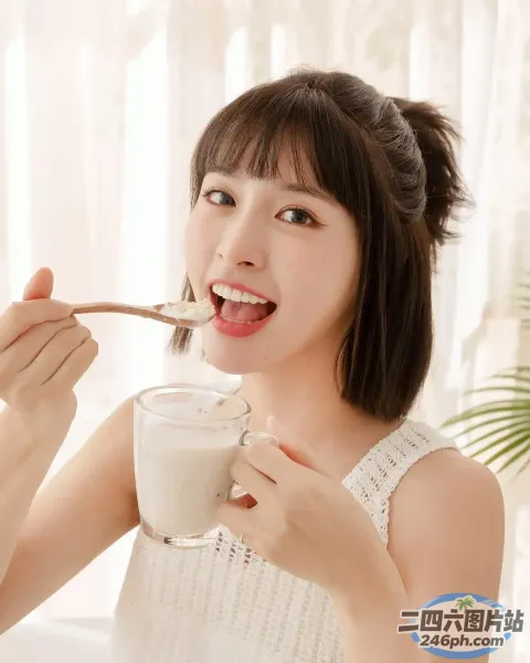 女人手里拿着勺子吃一杯牛奶