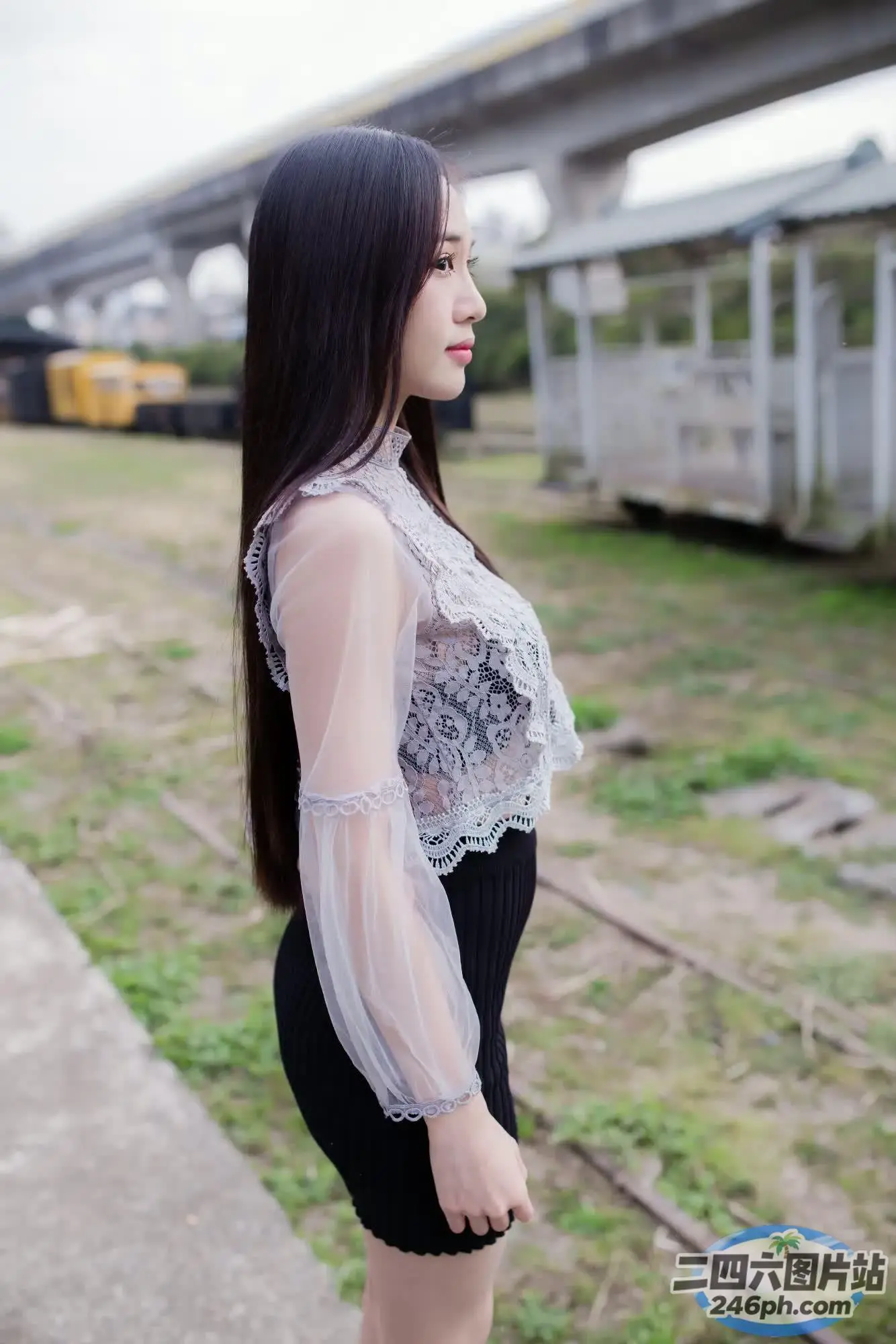 有一个女人站在火车轨道上，背景是一列火车