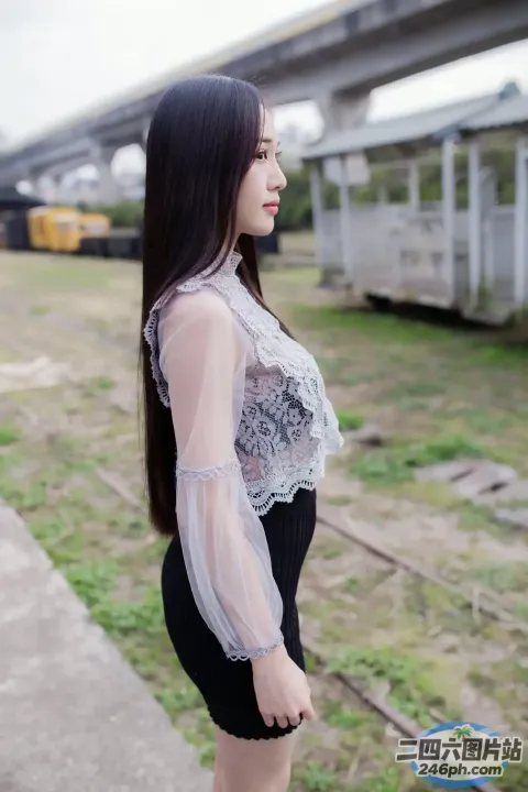 有一个女人站在火车轨道上，背景是一列火车