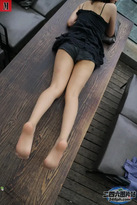 有一个女人躺在桌子上，双腿交叉