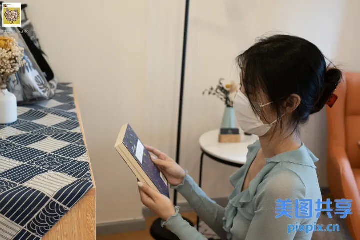 坐在桌子旁的女人在花瓶前看书