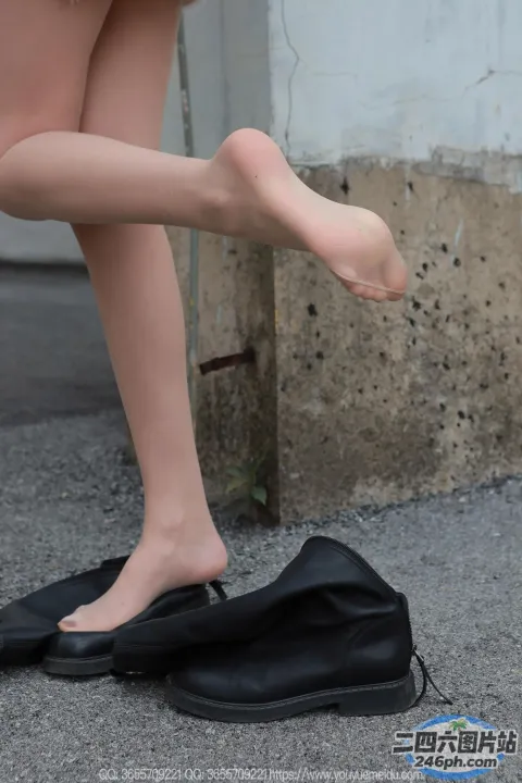有一个女人站在人行道上，脚放在一个袋子上
