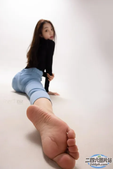 有一个女人坐在地板上，双脚抬起