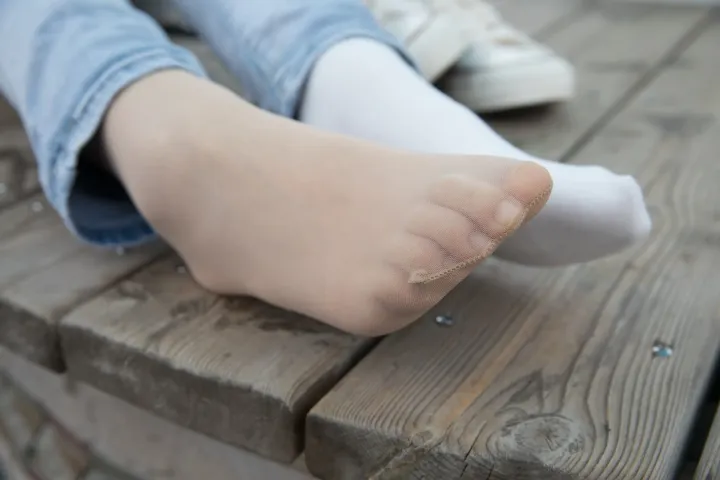 有一个人坐在长凳上，脚放在桌子上