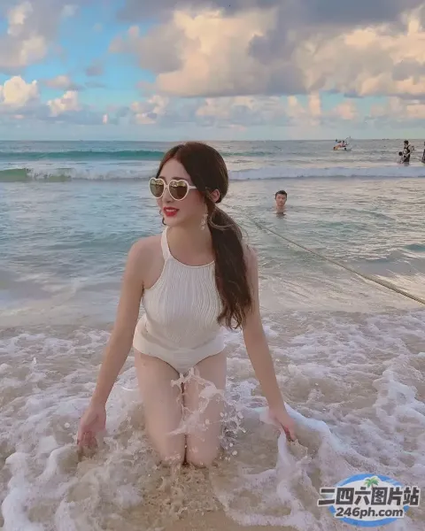 身穿白色泳衣的女子坐在海滩上的海浪中