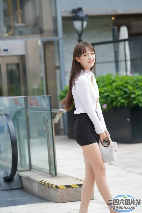 一名身穿短裙和白衬衫的女子走在人行道上