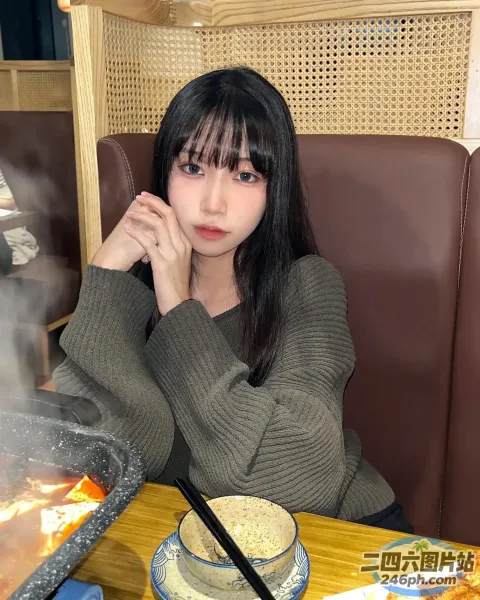 有个女人坐在一张桌子旁，桌上放着一盘食物