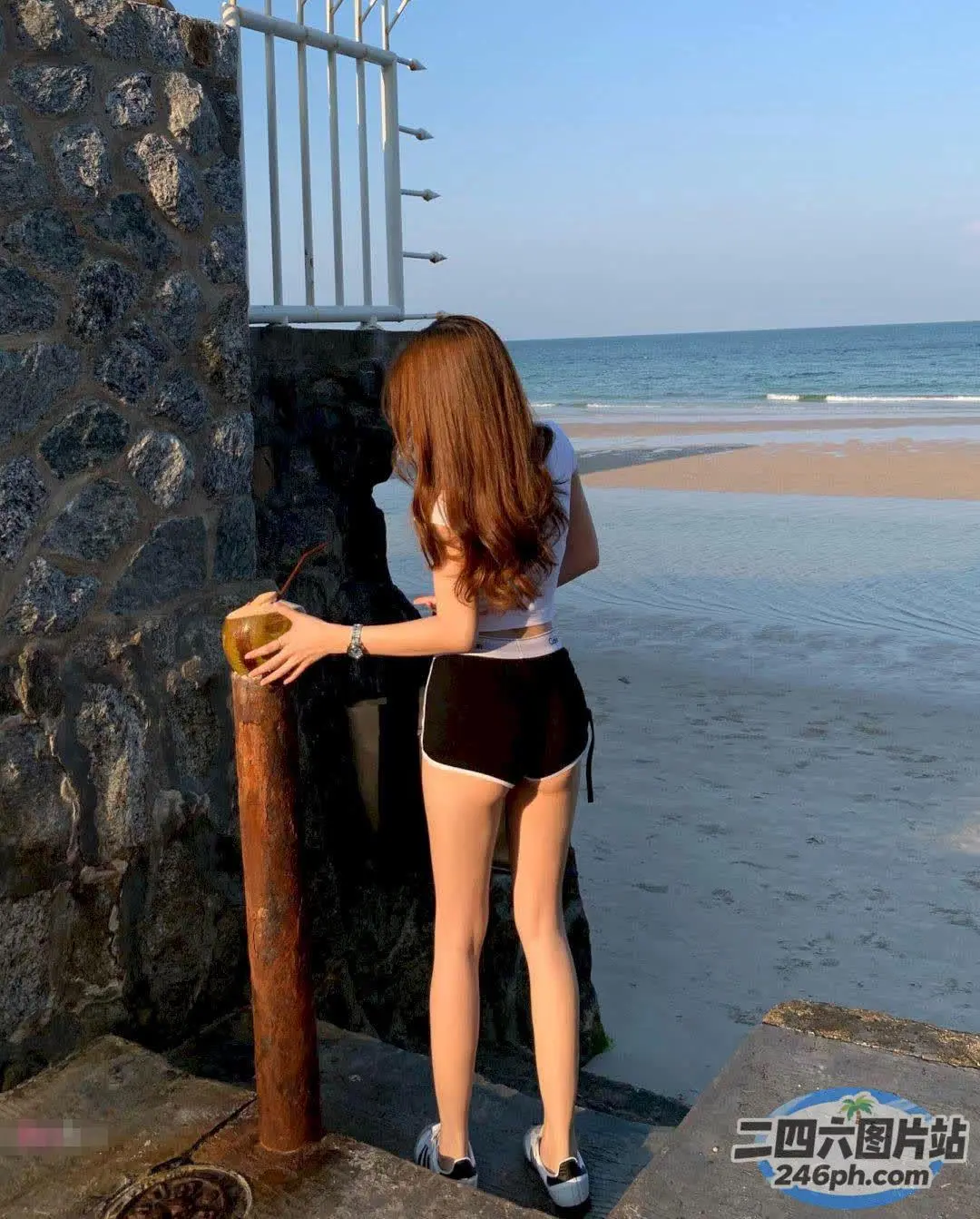 海边的石墙上站着一个女人