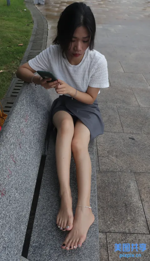 有个女人坐在长凳上用手机