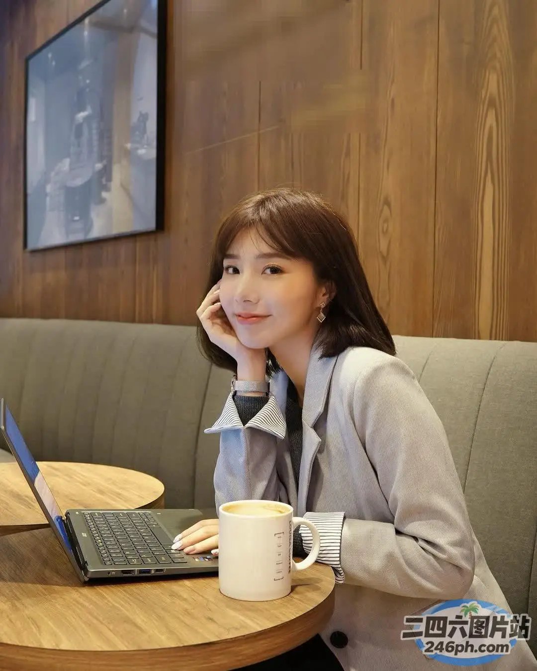 阿拉菲女人坐在桌子旁，手里拿着笔记本电脑和一杯咖啡