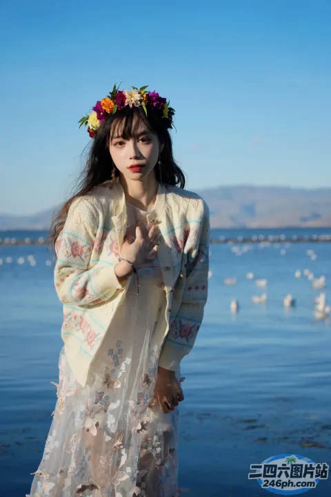 一个穿着白色连衣裙的女人站在水体旁边的海滩上