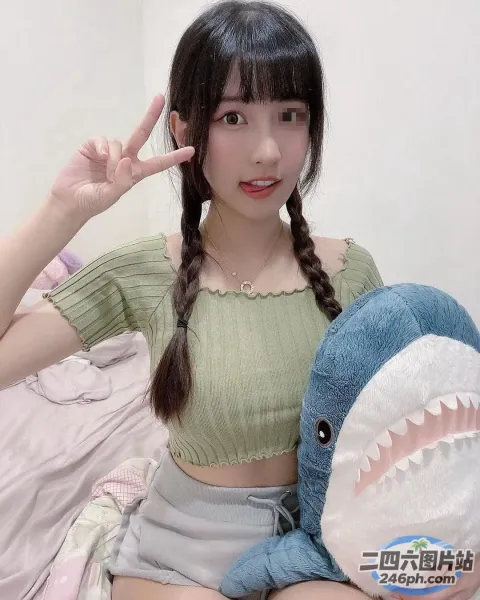 阿拉夫德亚洲女子坐在床上，手里拿着一条毛绒鲨鱼