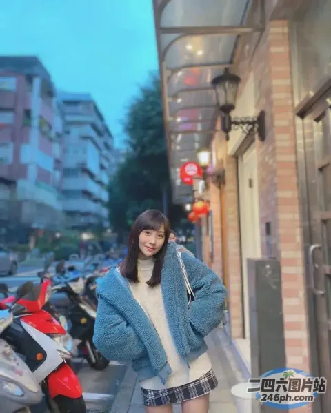 身穿蓝色夹克和格子裙的阿拉夫德女子站在人行道上