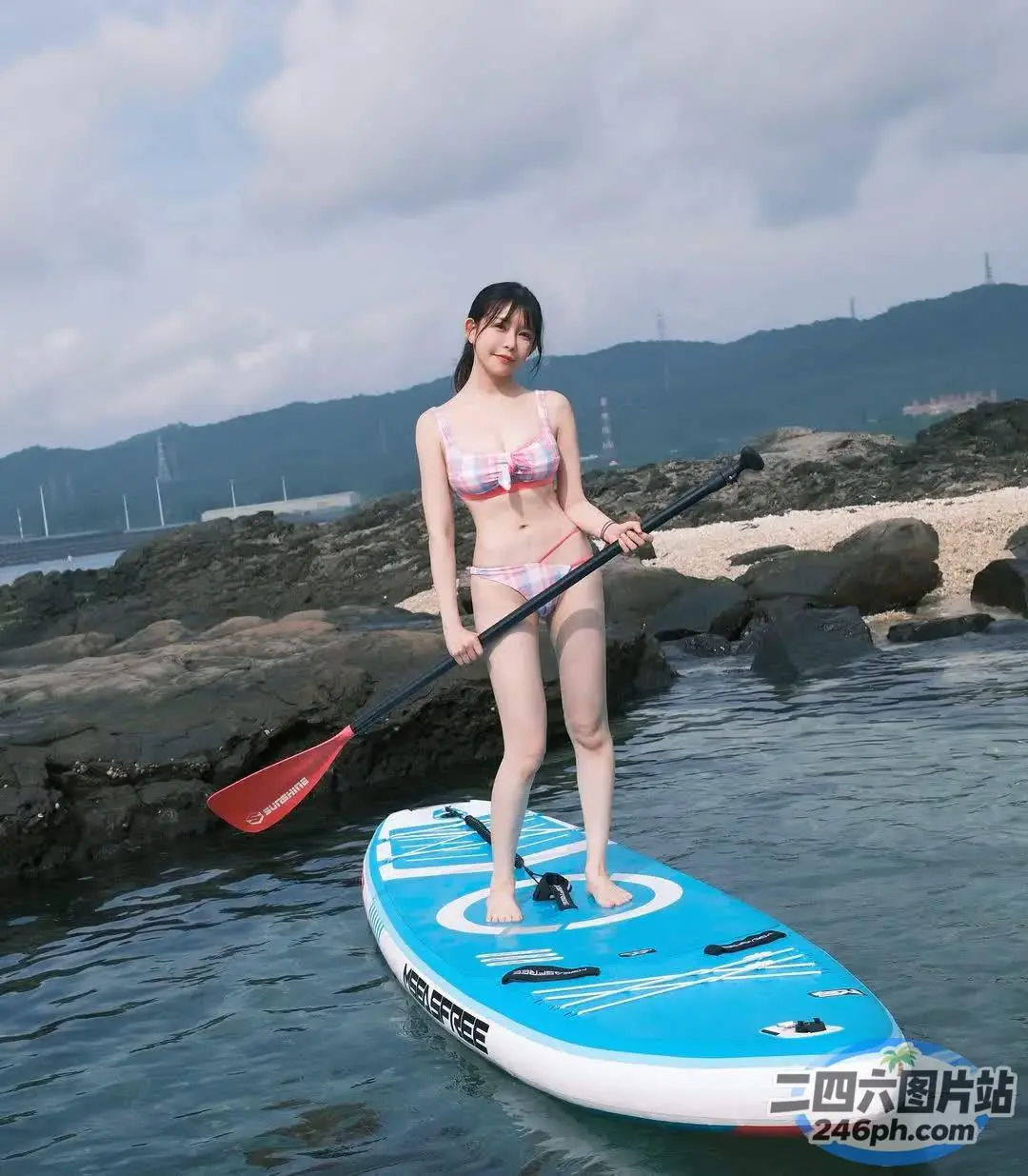身穿比基尼的 arafed 女子在水中的桨板上