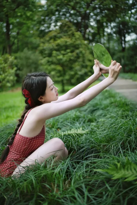 草地上坐着一个女人，手里拿着一片叶子