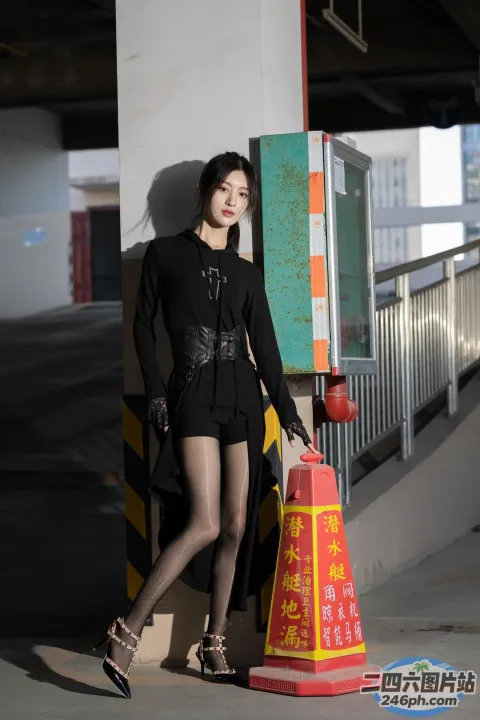 身穿黑色连衣裙和高跟鞋的 Araffe 女子站在交通锥旁边