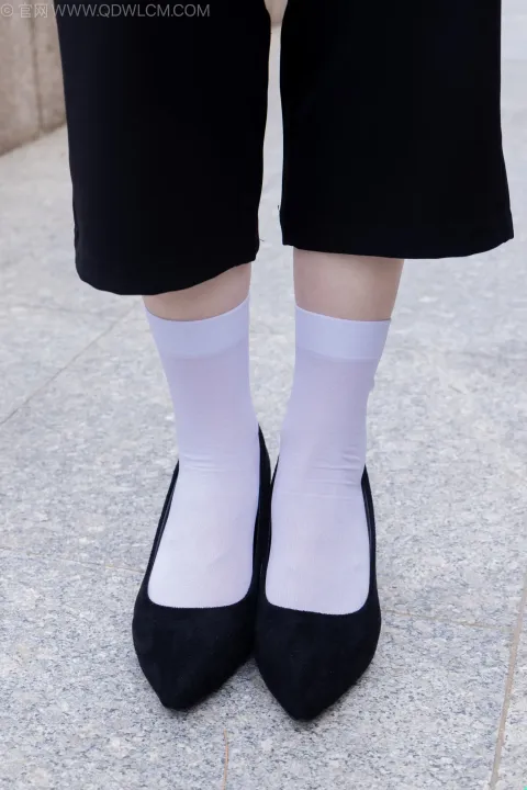 人行道上穿着黑色鞋子和白色袜子的双腿