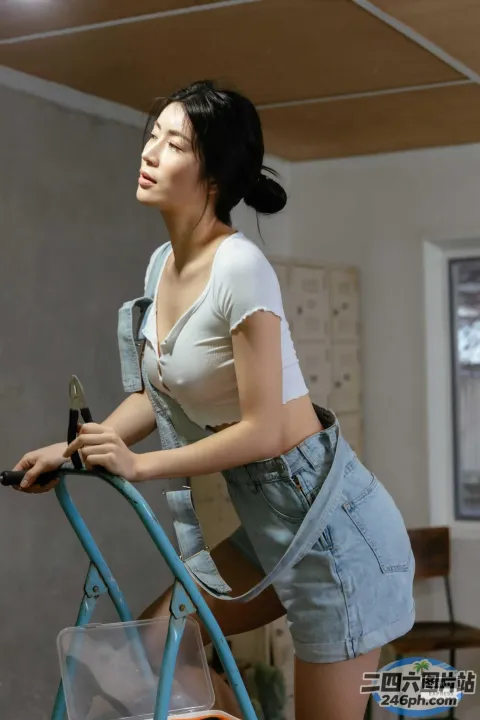 身穿白衬衫和蓝色短裤的阿拉夫德女子坐在一辆蓝色手推车上