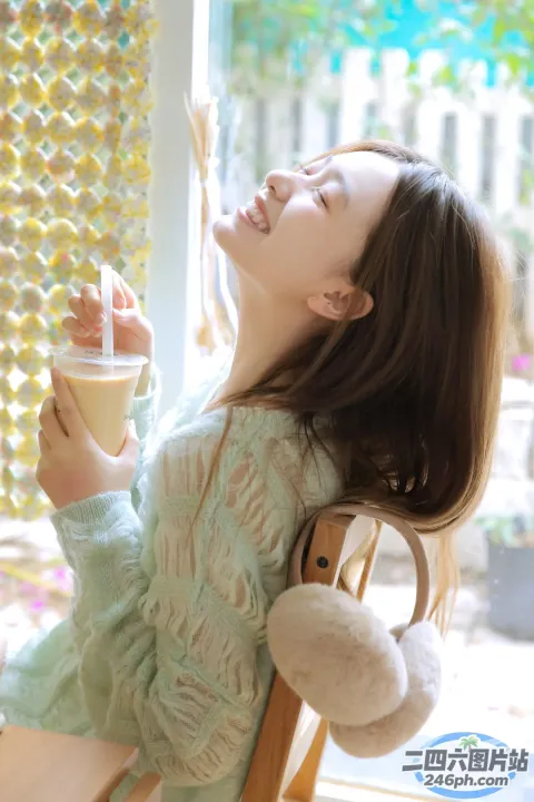 有一个年轻女孩坐在一张桌子旁，手里拿着一杯咖啡