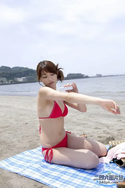 穿着红色比基尼的女人坐在海滩上的毛巾上