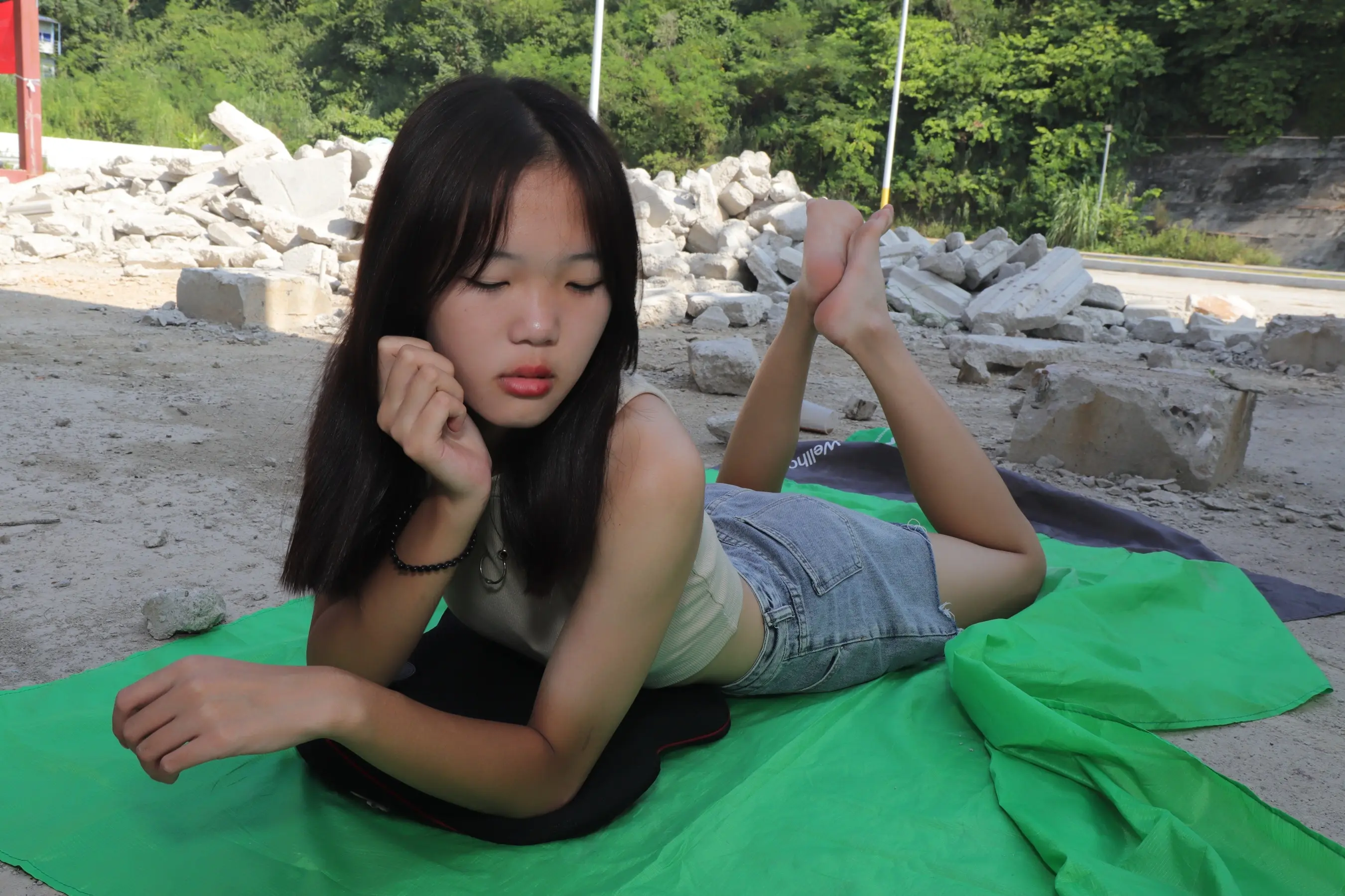 阿拉费德女人躺在地上的一条绿色毛巾上