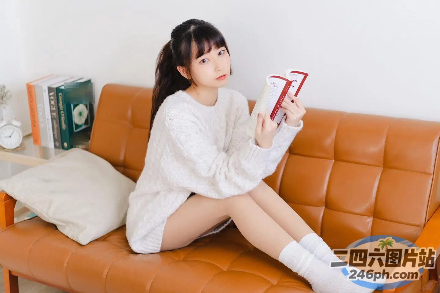 有一个女人坐在沙发上，手里拿着一本书
