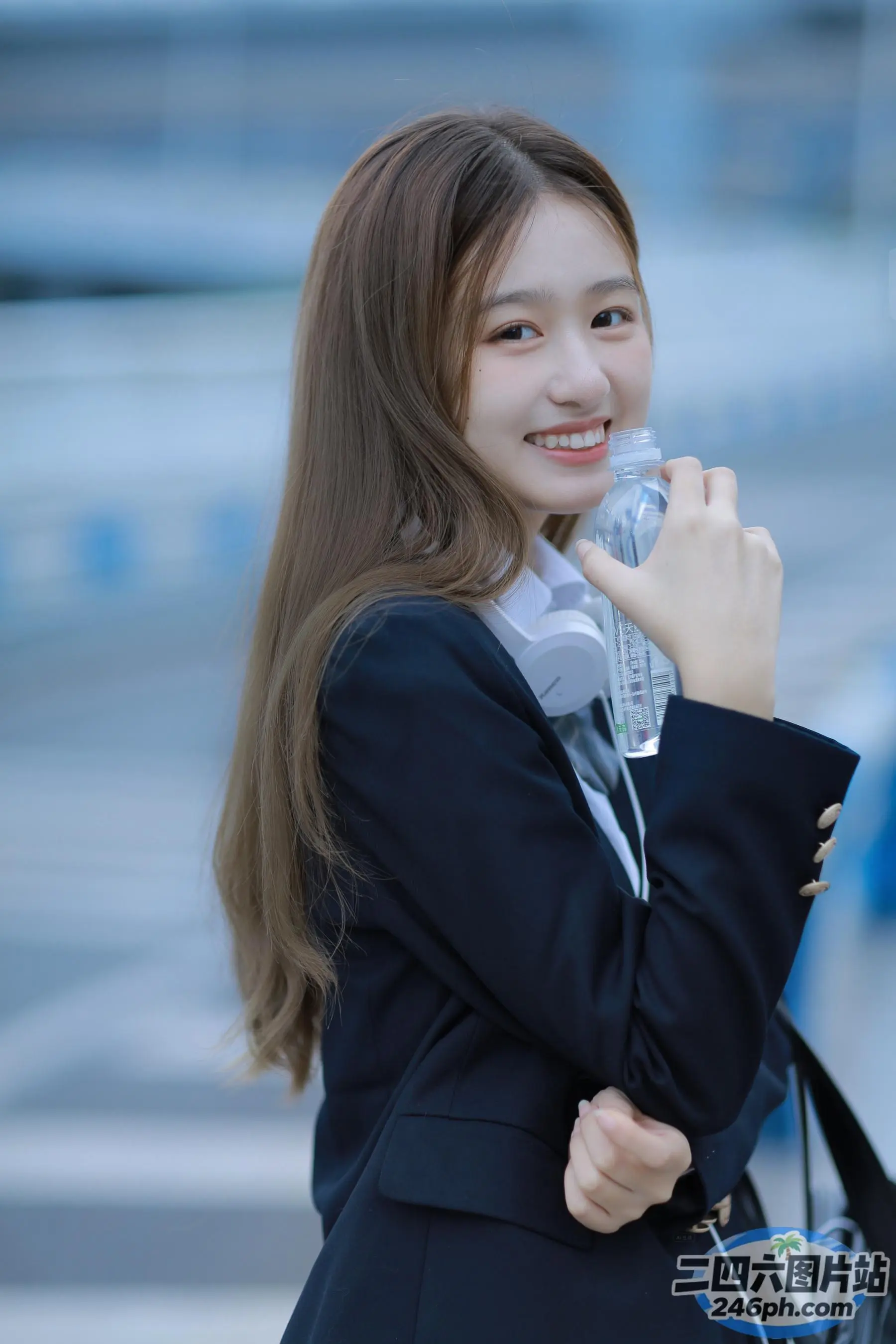 身穿黑色夹克和白色衬衫的 Arafed 女子，手里拿着一个水瓶