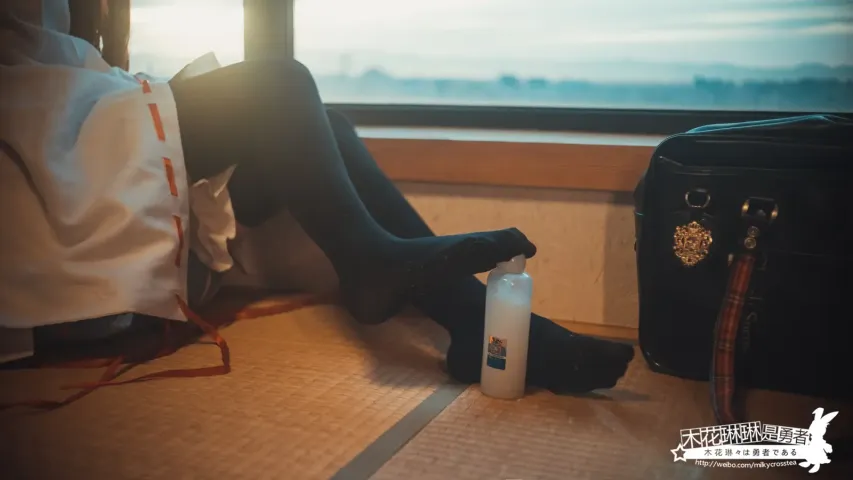 有人坐在地板上，抬起脚，拿着一瓶水