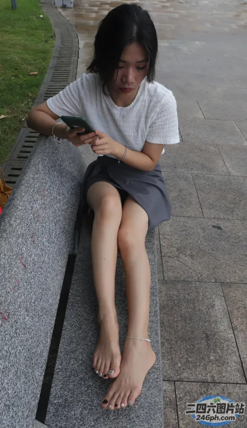 有个女人坐在长凳上用手机