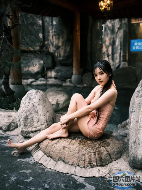 有一个女人穿着粉红色的裙子坐在岩石上