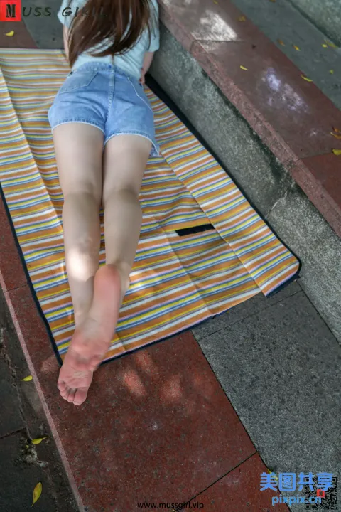 被拉夫的妇女躺在地上的毛巾上，双脚抬起