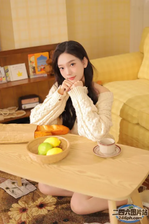 有个女人坐在桌子旁，手里拿着一碗水果