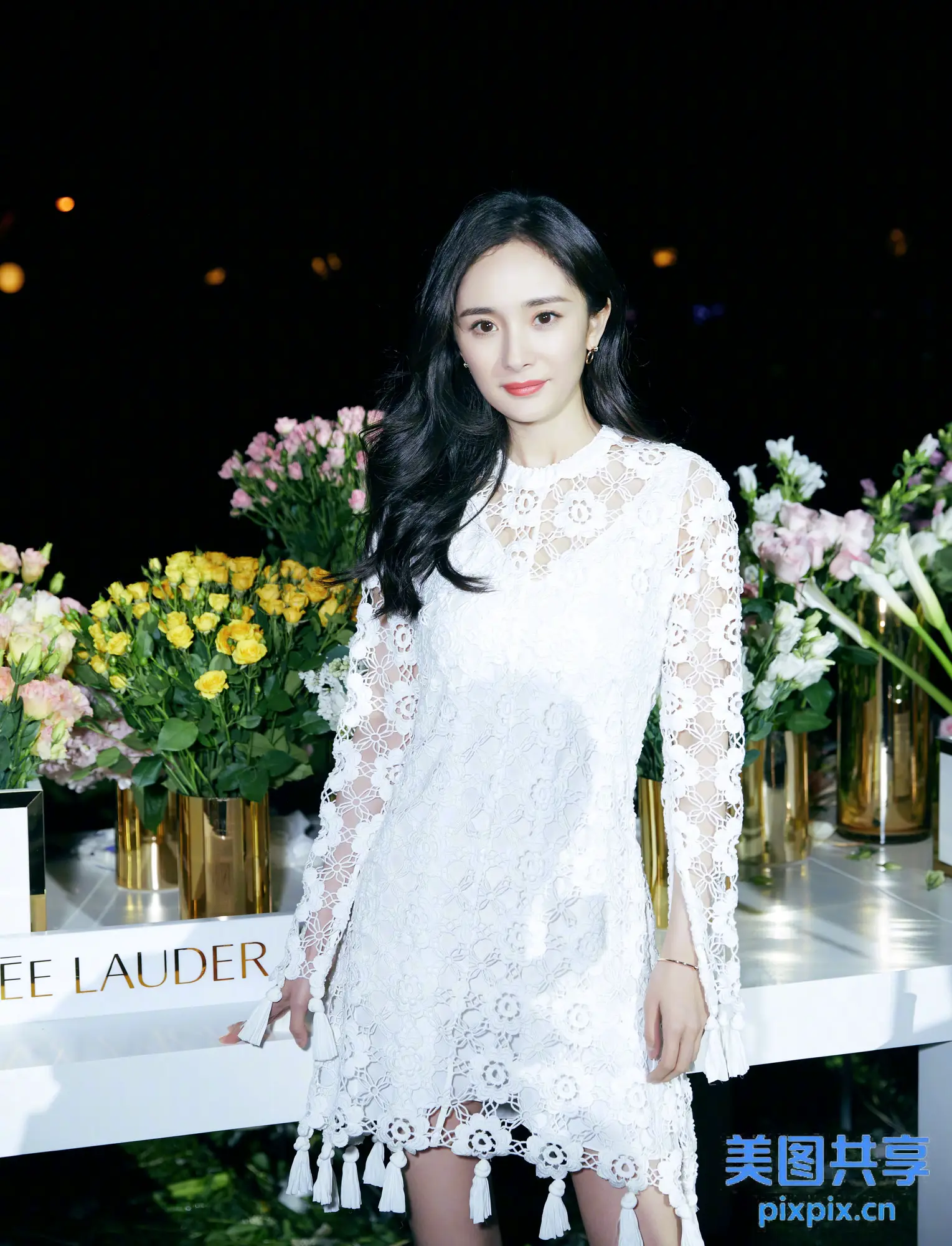 有个女人站在摆满鲜花的桌子前