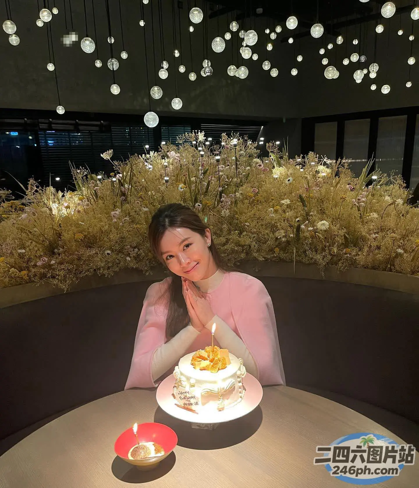 坐在桌子旁的女人，面前放着蛋糕和蜡烛