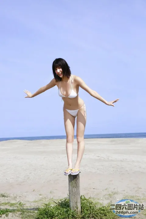 身穿白色比基尼的 arafed 女子站在海滩上的杆子上