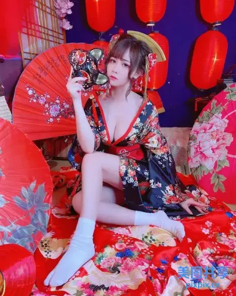 穿着和服的阿拉伯女坐在床上，手里拿着一把红扇子